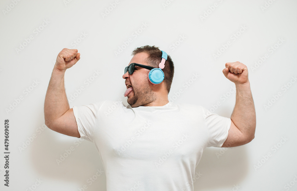 Close-up portrait of funny guy dancing and listening to music using a smartphone music application in headphones . Party man Close-up portrait of funny guy dancing and listening to music using a smartphone music application in headphones . Party man