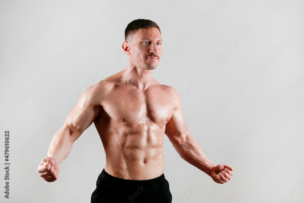 Professional bodybuilder posing over isolated white background. Studio shot of a fitness trainer flexing the muscles. Close up, copy space.