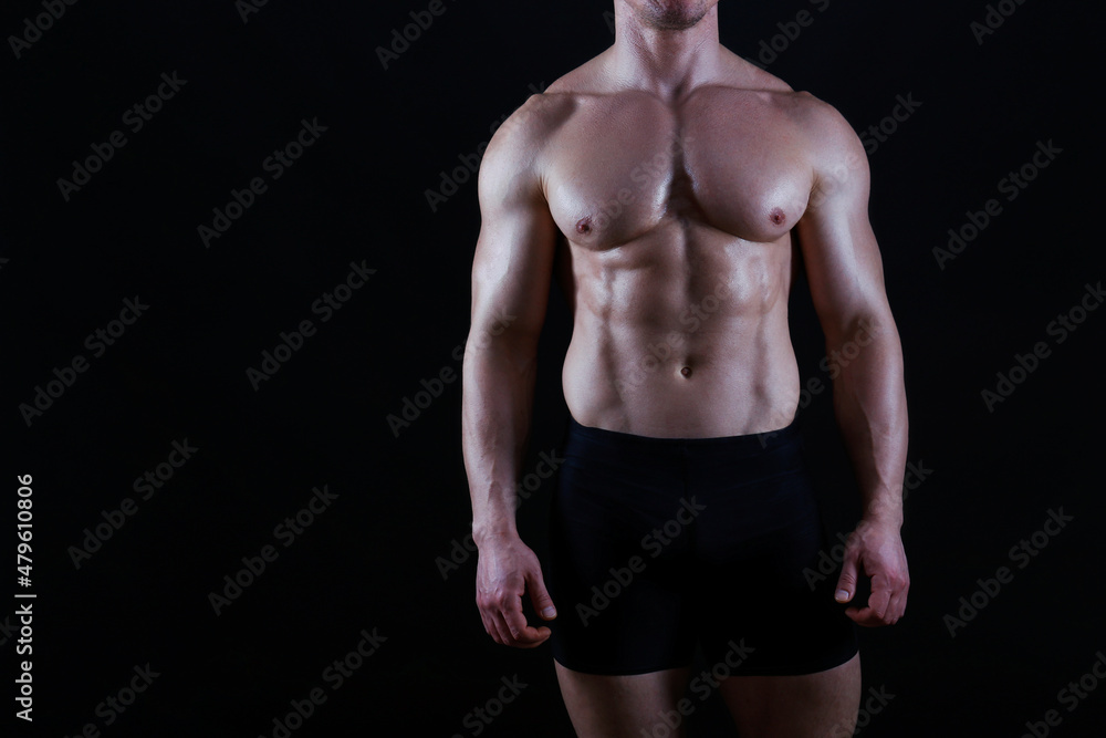 Fototapeta premium Professional bodybuilder posing over isolated black background. Studio shot of a fitness trainer flexing the muscles. Close up, copy space.