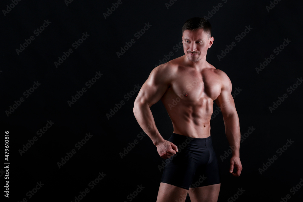 Professional bodybuilder posing over isolated black background. Studio shot of a fitness trainer flexing the muscles. Close up, copy space. Professional bodybuilder posing over isolated black background. Studio shot of a fitness trainer flexing the muscles. Close up, copy space.