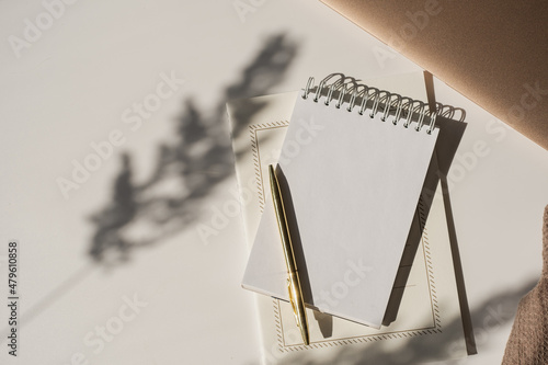 Aesthetic luxury workspace template. Spiral flip notebook with copy space in plant sunlight shadow on white background. Schedule, notes concept for blog, social media, web photo