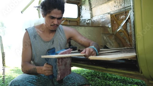 Craftsman polishing wooden plank near carava photo