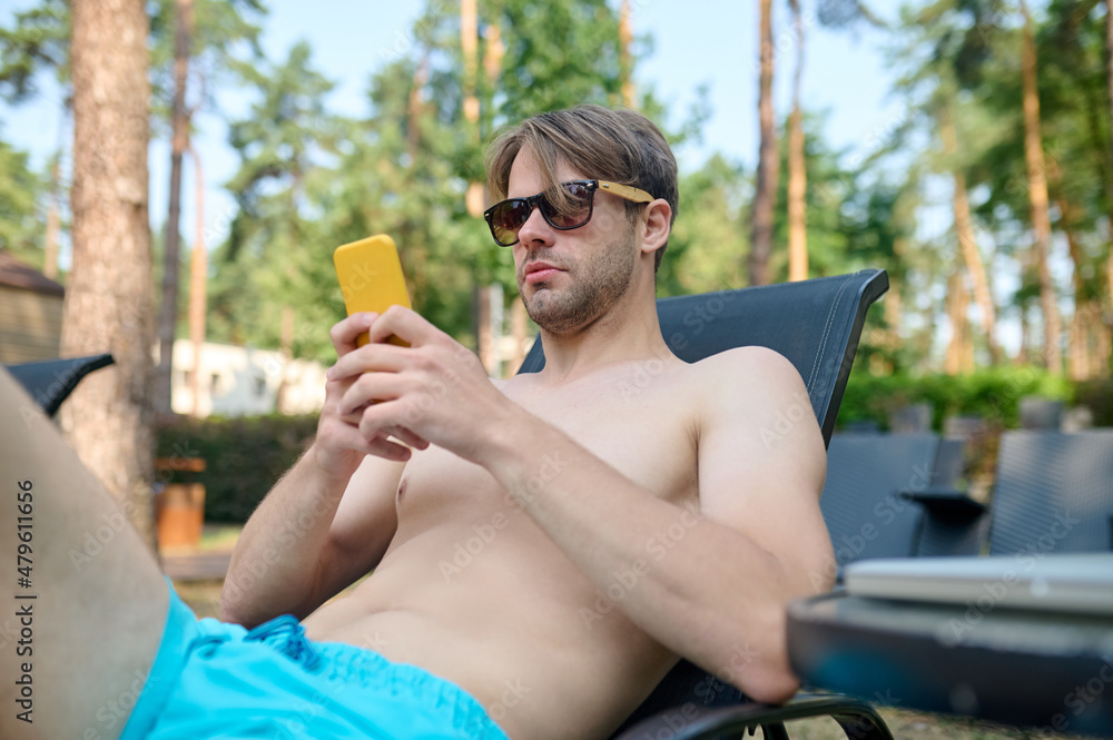 A young man in sunglasses with a smartphone in hands A young man in sunglasses with a smartphone in hands