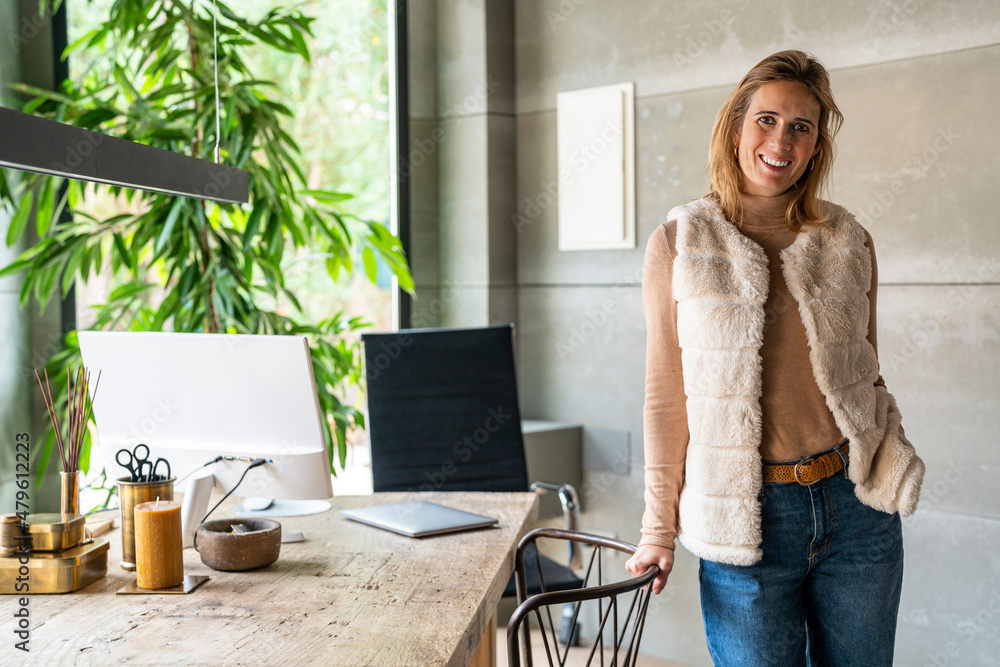 Content woman standing near desktop