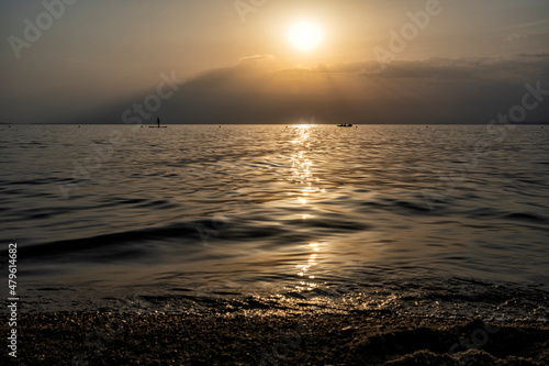 Silhouette of unrecognizable woman in wetsuit paddling on a SUP board. Female floating on a stand up paddle board in the gulf. Summer season and active leisure concept. Dynamic recreation.