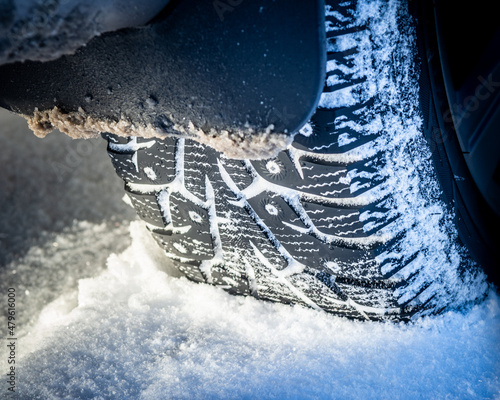 Winter tires with studs on the snow, creative photo. Winter car wheels on a snowy road, close-up. photo