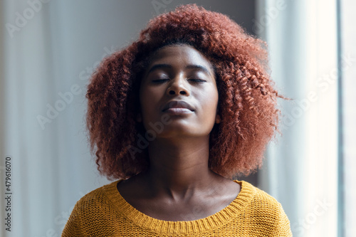 Relaxing woman looking up while relaxes taking a deep breath standing in the living room at home.