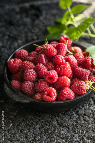 Raspberries in bowl on a dark wooden table, selective focus. Ingredients for raspberry juice or desserts. Raspberries on bowl. Raspberry with copy space for text. Various fresh summer berry . 