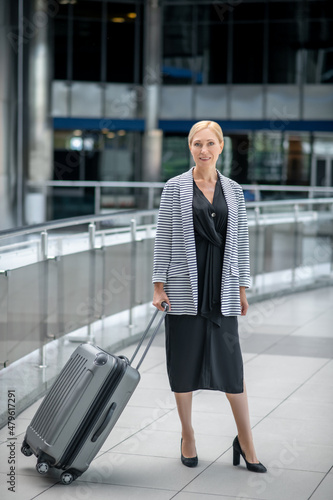 Cheerful businesswoman with her baggage standing at the airport terminal