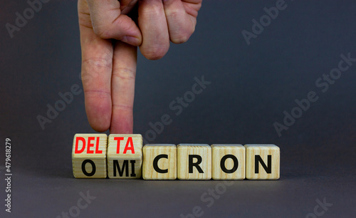 Covid-19 omicron or deltacron symbol. Doctor turns cubes and changes the word omicron to deltacron. Beautiful grey background. Medical, covid-19 corona omicron or deltacron concept. Copy space.
