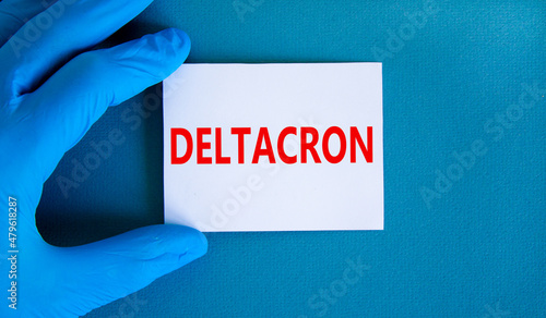 Covid-19 corona deltacron variant symbol. Hand in blue glove with white card. The concept word Deltacron. Medical and COVID-19 corona deltacron variant concept. Copy space.