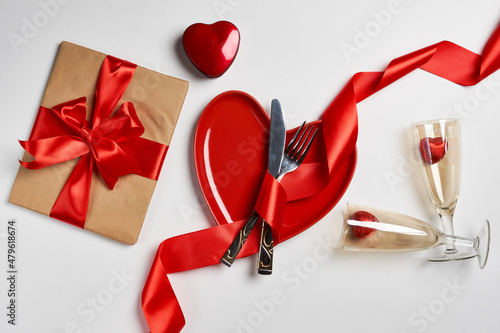 Fork, spoon, champagne glasses, heart shaped plate and gift box with red ribbon and bow, valentine's day and the concept of love
