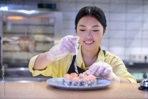 Asian woman putting sushi on the plate and looking inspired photo