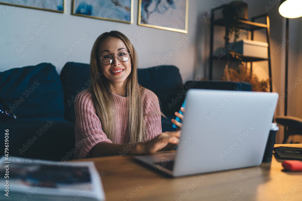 European girl in glasses using laptop at home