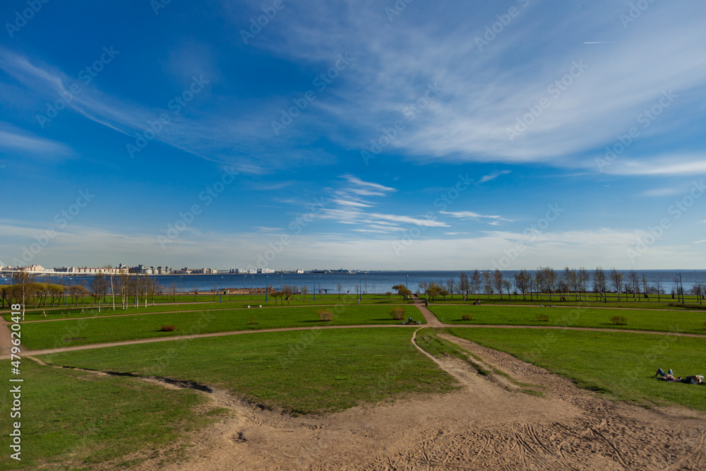 Spring landscape. Blue sky, green grass, view of the bay.