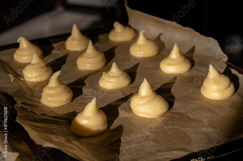 Choux dough for profiteroles on baking paper, beautiful sunshine. photo