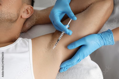 Cosmetologist injecting man's armpit, closeup. Treatment of hyperhidrosis photo