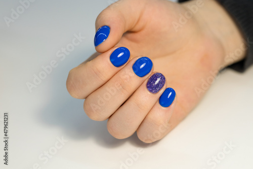 Bright festive, New Year's, blue manicure on female hands. Nail design. The process of creating a manicure. Perfect blue manicure. Close-up of female hands with blue nails. Gel polish on nails. 