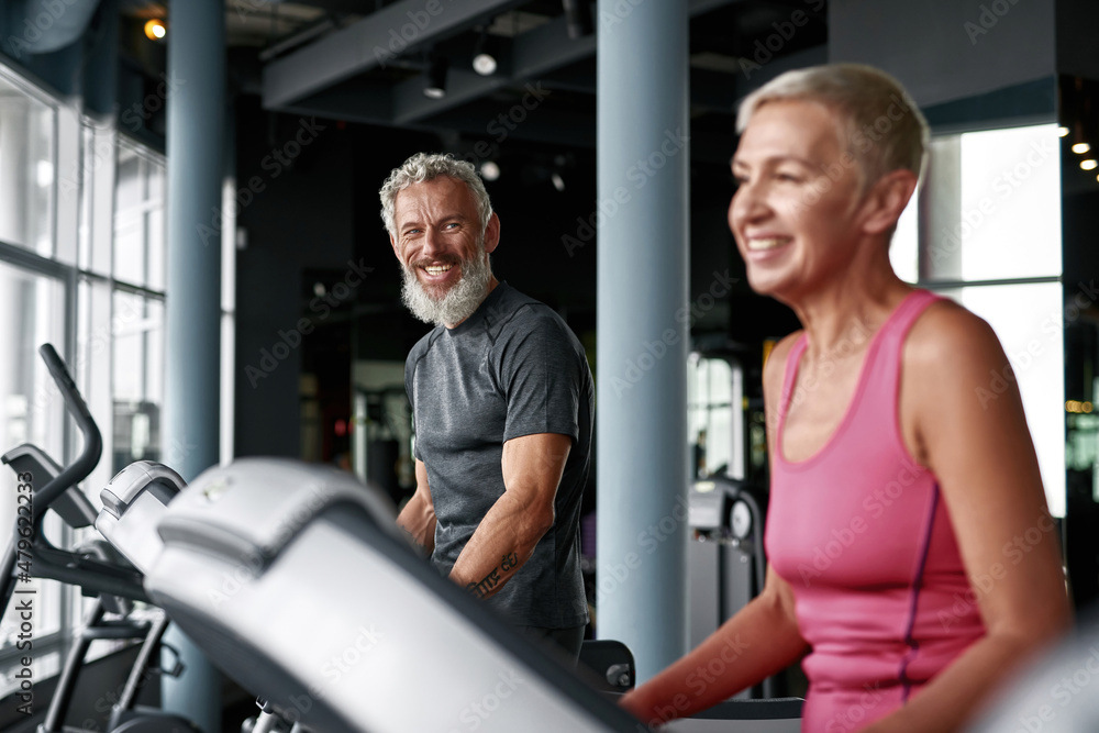 Cheerful elderly couple working out on stepping machine Cheerful elderly couple working out on stepping machine