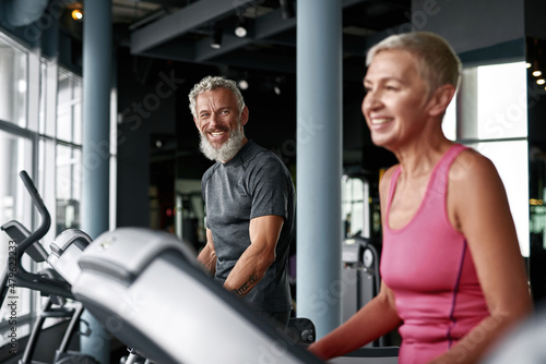 Cheerful elderly couple working out on stepping machine