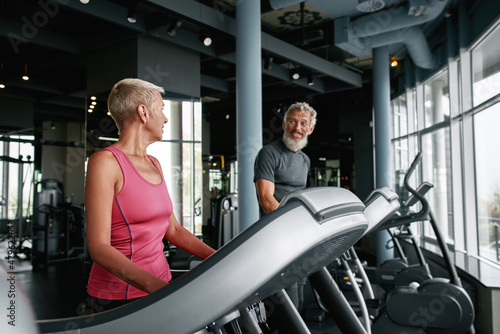 Indoor cardio workout. Elderly man and woman walking on treadmill