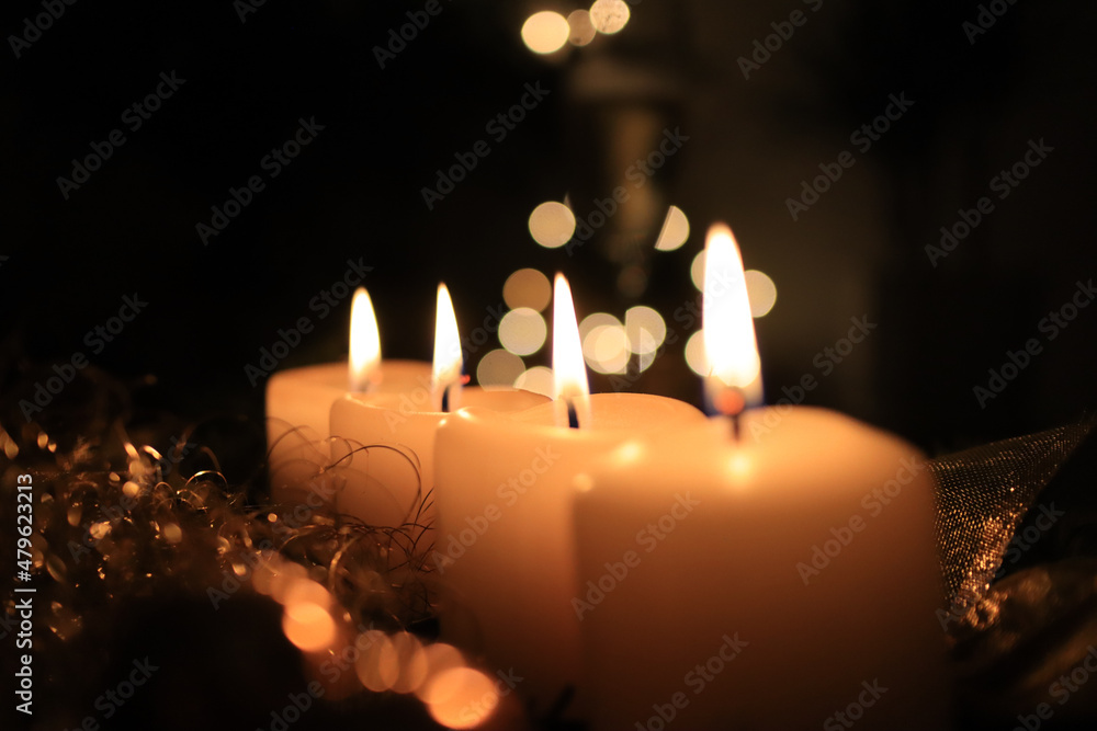 Four burning white advent candles in a row