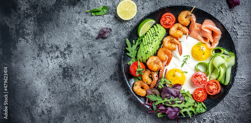 Ketogenic breakfast. Keto low carb salmon, grilled shrimps, prawns, fried eggs, fresh salad, tomatoes, cucumbers and avocado. keto diet. Top view © Надія Коваль