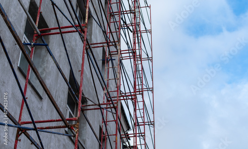 Scaffolding set on a house under construction on cloudy blue sky background