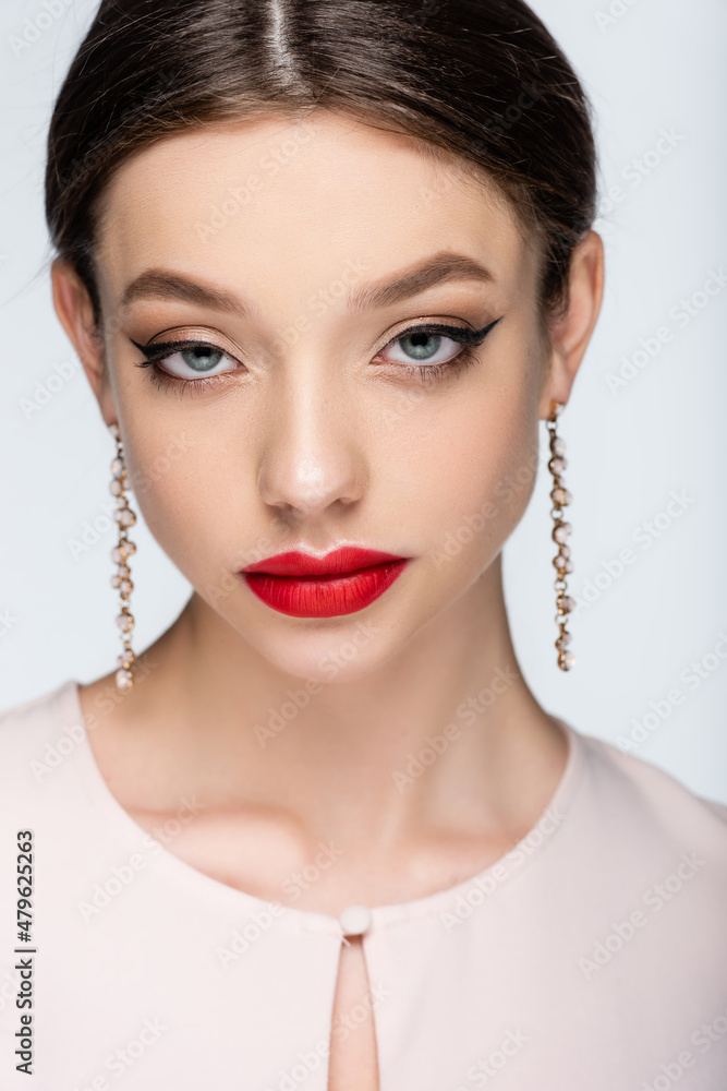 brunette woman in earrings with red lips looking at camera isolated on grey brunette woman in earrings with red lips looking at camera isolated on grey