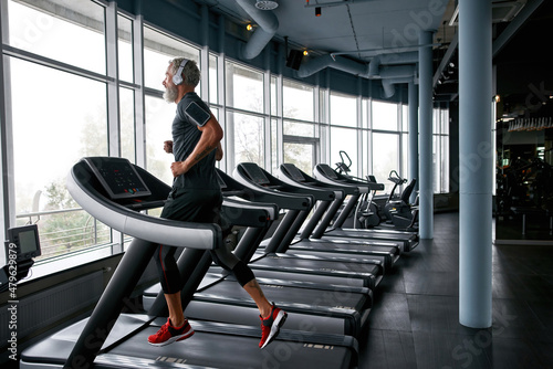 Athletic man in gym, performing cardio workout, running