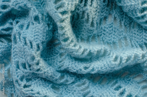Fragment of a knitted woolen plaid close-up. blue threads, large knitting pattern, all the loops are visible.