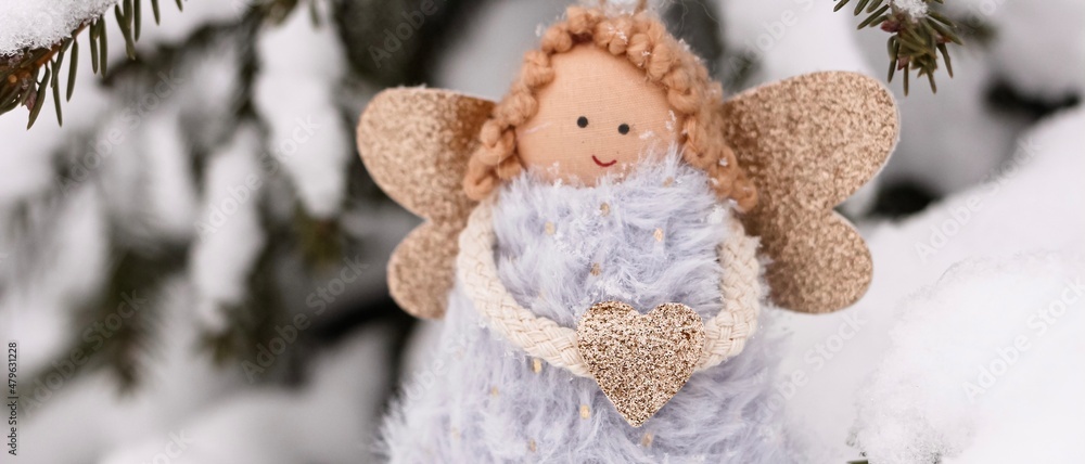 A soft textile doll with golden heart in hands sitting on the snow. Valentine’s Day, love, Merry Christmas, New Year concept. Banner. A soft textile doll with golden heart in hands sitting on the snow. Valentine’s Day, love, Merry Christmas, New Year concept. Banner.