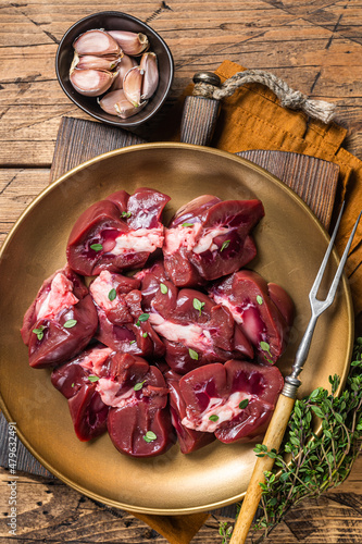 Lamb kidney, raw sliced offal on plate with thyme. Wooden background. Top view