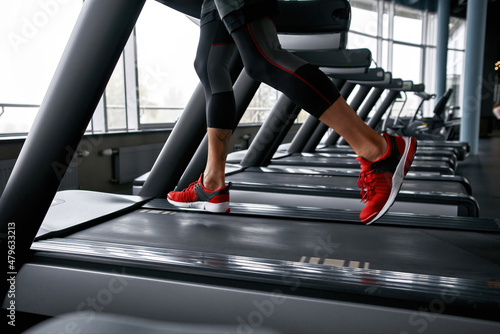 Closeup male legs in red trainers running on treadmill
