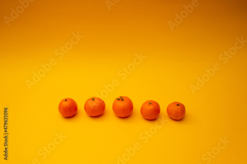 Bright orange tangerines lie on a yellow background