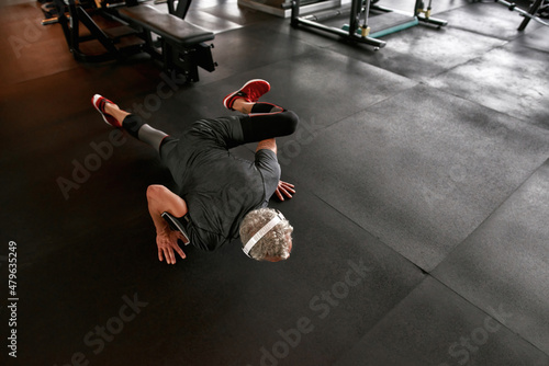 Faceless man on floor doing planks at gym