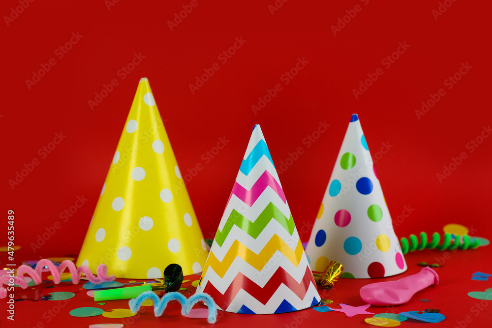 Colorful party hats and other festive items on red background Colorful party hats and other festive items on red background