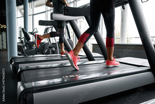 Lower legs part of fitness woman and man running on running machine