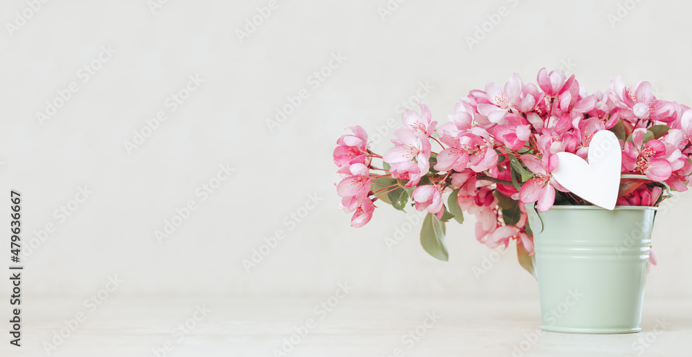 Heart in pink spring flowers in a bucket. Pastel blurred background. Banner copy space. Mothers day, St Valentines Day birthday spring wedding or anniversary greeting card. Flowers delivery. Florists Heart in pink spring flowers in a bucket. Pastel blurred background. Banner copy space. Mothers day, St Valentines Day birthday spring wedding or anniversary greeting card. Flowers delivery. Florists