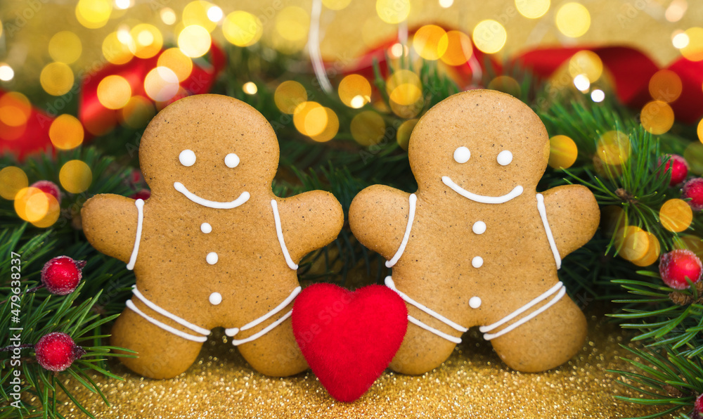 Festive composition with two gingerbread men and red heart on glitter golden background. Valentine's Day card. Close-up.