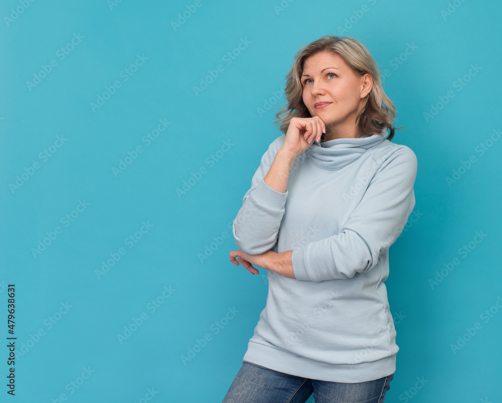 Attractive smiling blond woman thinking and looking up on blue background with copy space. Attractive smiling blond woman thinking and looking up on blue background with copy space.