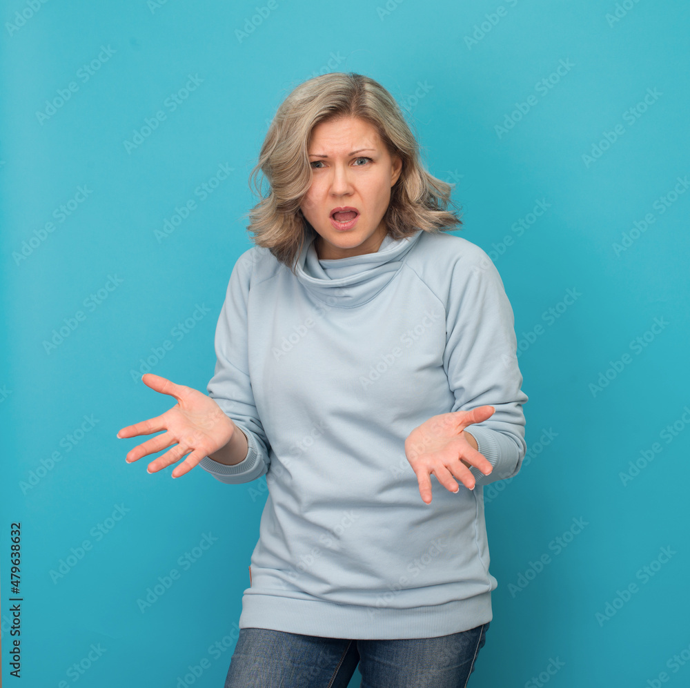 Aggressive stressed furious blond woman arguing isolated on blue background. Irritation, misunderstanding concept. Aggressive stressed furious blond woman arguing isolated on blue background. Irritation, misunderstanding concept.