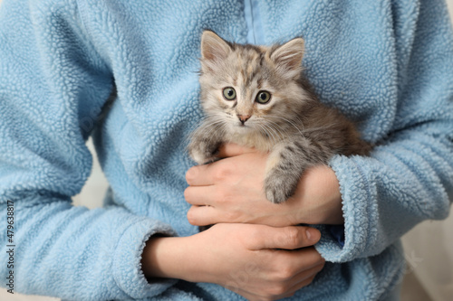 Woman holding cute fluffy kitten, closeup view