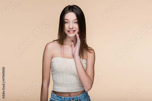 happy young woman in crop top with bare shoulders isolated on beige
