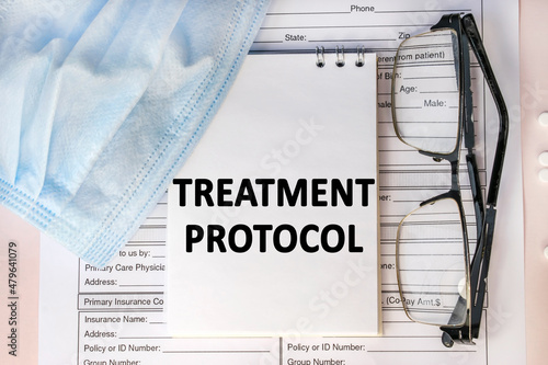 the treatment protocol is written on a notebook that is on the sick-list. Medical mask and eyeglasses photo