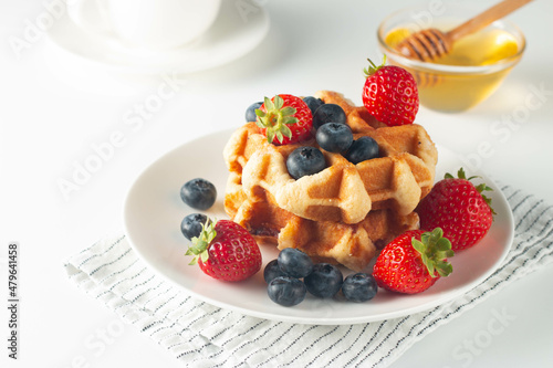 Fresh homemade food of berry Belgian waffles with honey  chocolate  strawberry  blueberry  maple syrup and cream. Healthy dessert breakfast concept with juice