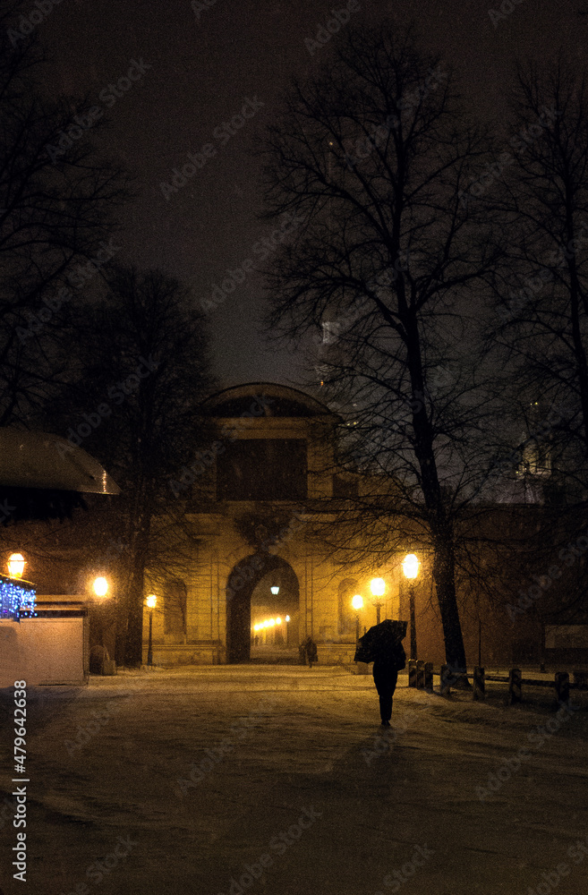 Silhouette of a man with an umbrella under a snowfall in a night city. Twilight in the city.