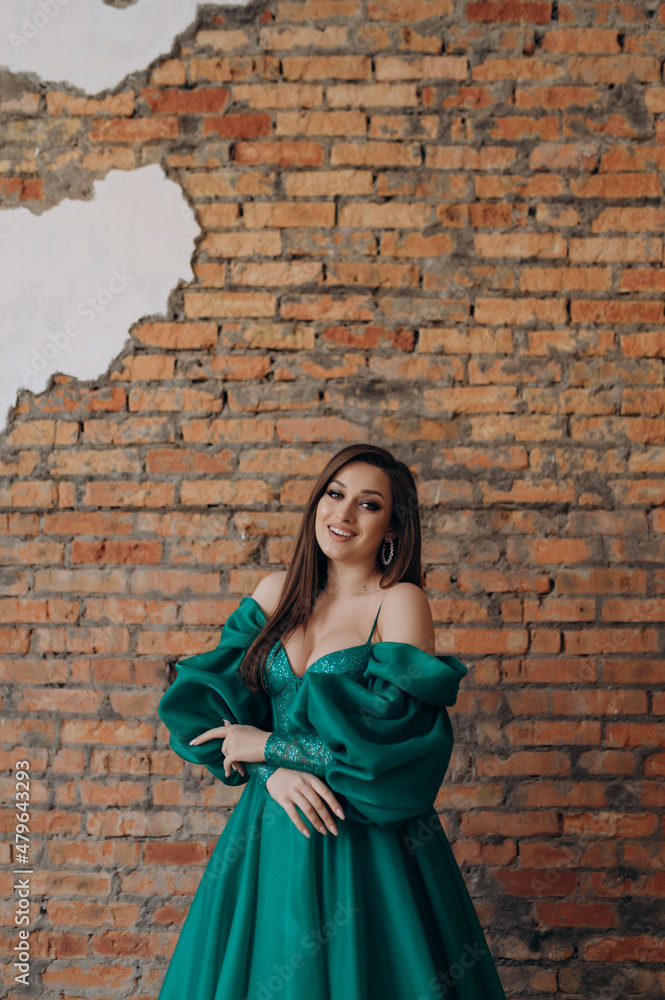 A beautiful girl in a green dress smile shows a brick wall dress A beautiful girl in a green dress smile shows a brick wall dress