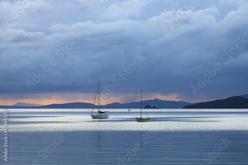 Alone sailboats at sunset. Atmospheric seascape with reflection
