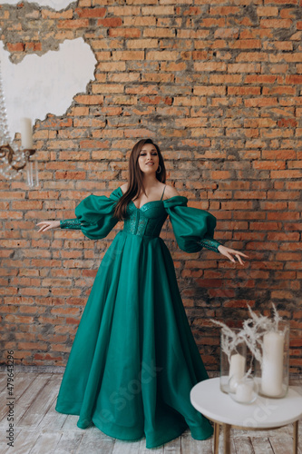A beautiful girl in a green dress smile shows a brick wall dress